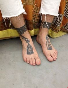 a man's feet with tattoos on them and his leg chained to the ground