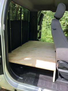 the back end of a green van with its cargo door open and wood flooring