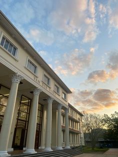 an old building with columns and steps leading up to the front door at sunset or dawn