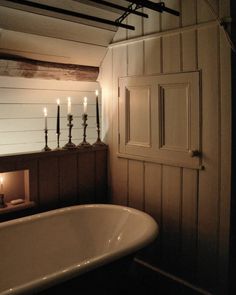 an old fashioned bathtub with candles on the wall