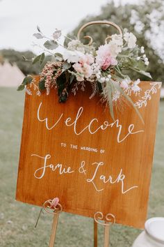 a wooden sign with flowers on it that says welcome to the wedding of jamie and lark