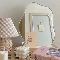 a table topped with books and candles next to a mirror on top of a wooden shelf