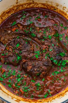 a pot filled with meat and vegetables on top of a wooden table