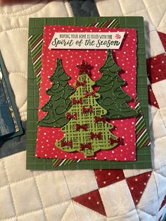 a christmas card on a quilted tablecloth with an ornament in the shape of a tree