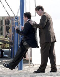 two men standing next to each other on a swing