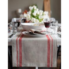 a dining table set for two with wine glasses and silverware on the place setting