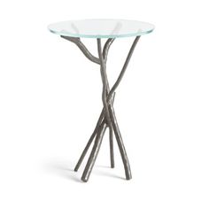 a glass and metal table with two branches on the top, one standing upright in front of it