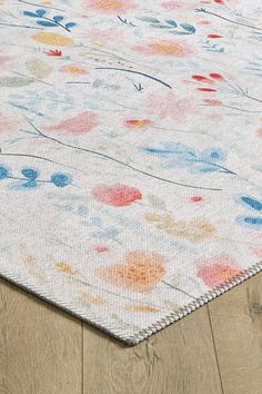 an area rug with multicolored flowers and leaves on the floor, in front of a wooden floor