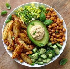 a white bowl filled with vegetables and chickpeas on top of a wooden table