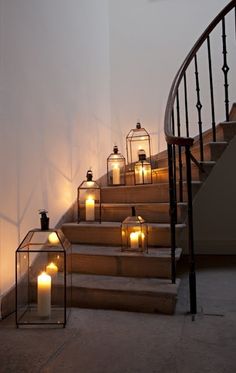 candles are lit on the steps in front of a staircase with glass lanterns and wrought iron handrails