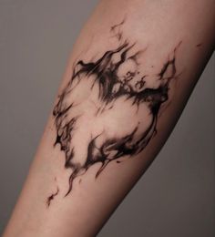 a black and white photo of a tattoo on someone's arm with ink swirling around it