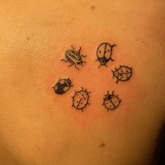 a ladybug tattoo on the back of a woman's upper back shoulder