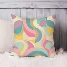 a colorful pillow sitting on top of a white furnishing next to a wooden wall