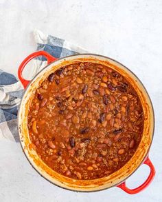 a red pot filled with chili and beans on top of a blue and white checkered towel