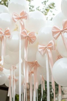 white balloons with pink bows and ribbons hanging from them