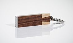 a wooden keychain is shown on a white surface with a reflection in the foreground