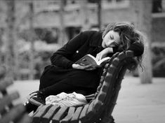 a woman sitting on a bench reading a book