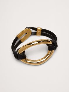 A bold exploration of contrasting textures, this bracelet juxtaposes a fluid oval against luxurious leather.  Here, artisans handcraft each piece from either 14k-gold or 999-silver plated brass.  14k-gold or sterling-silver plated.  Adjustable slider clasp.  Diameter: 2. 4" Elegant Leather Bracelets With Gold-tone Hardware, Gold Leather Bracelets With Gold-tone Hardware, Modern Gold Leather Bracelet With Gold-tone Hardware, Modern Adjustable Bracelets With Gold-tone Hardware, Modern Gold Leather Bangle Bracelet, Modern Adjustable Jewelry With Gold-tone Hardware, Adjustable Gold Leather Bracelet With Gold-tone Hardware, Modern Oval Link Bracelets With Gold Clasp, Chic Leather Bracelet Jewelry