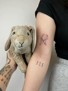 a person holding a small stuffed animal in their arm with the word eef tattooed on it