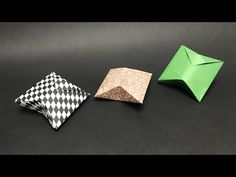 three different colored origami pieces sitting on top of a black table next to each other