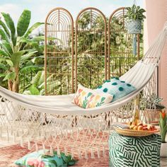 a white hammock sitting on top of a patio next to a potted plant