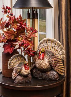 two turkey figurines sitting on a table next to a lamp