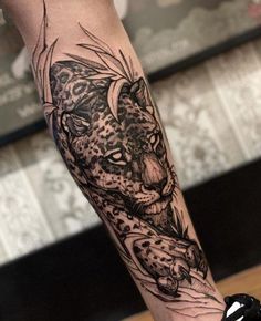 a black and white tattoo of a leopard on the left leg with an arrow in its mouth