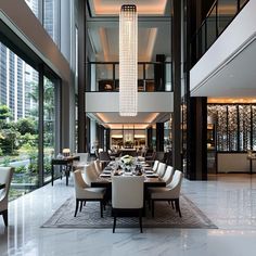 an elegant dining room with chandelier and white chairs in front of large windows