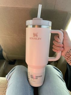 a person sitting in the back seat holding a coffee cup with a straw sticking out of it