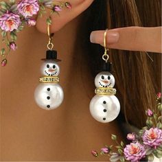 a close up of a person wearing earrings with snowmen on them