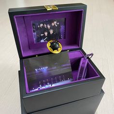 an open black box with purple and gold decorations in it on top of a wooden table