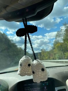 two stuffed animals hanging from the dashboard of a car