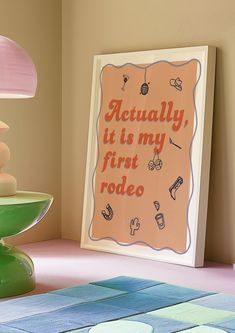 a sign that says actually it is my first rodeo on the wall next to a lamp