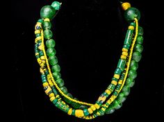 A multi-strand necklace of green and yellow trade beads. There are yellow whitehearts, millefiori, and eye beads in green and yellow tones, old Bohemian trade beads, and a more contemporary green Krobo recycled glass beads, creating a pleasing mix of yellows and greens in this ensemble of African beads of several centuries. The necklace is approximately 24" long. The beads range from tiny 3mm yellow whitehearts to 15mm Krobo beads; The two large green Krobo glass beads aggregating the strands ar Traditional Green Multi-strand Beads, Krobo Beads, Unusual Necklace, Recycled Glass Bead, Double Strand Necklace, African Trade Beads, Eye Beads, Yellow Tones, African Beads