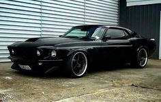 a black muscle car parked in front of a garage