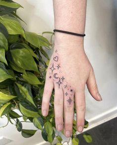 a person's hand with a small star and moon tattoo on it