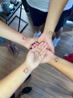 several people are holding hands in the middle of a circle with symbols on their wrists