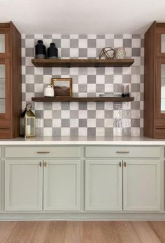 an empty kitchen with white cabinets and checkered wallpaper on the walls, along with wooden flooring