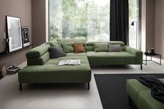 a living room with green couches and black rugs on the floor in front of a large window