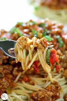 a fork full of spaghetti with meat and vegetables