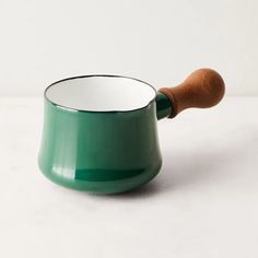 a green cup with a wooden handle on a white surface