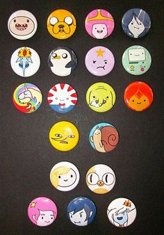 a bunch of buttons that are sitting on a black surface with faces drawn on them