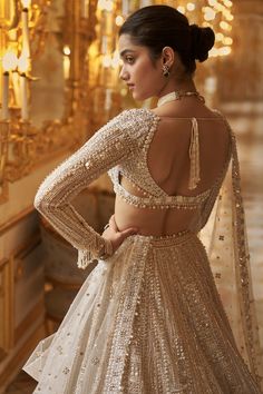 This lehenga set features delicate embroidery in ivory and gold sequin in a geometric pattern,. The full sleeves blouse has a plunging neckline and shows pearl and crystal tassels at the waist and wrist. It is paired with a matching four sided embroidered dupatta.From Seema Gujral's Inara collection. DELIVERY TIMEPlease allow 8-12 weeks for your outfit to arrive. FABRIC DETAILSNet Professional cleaning only. Sequin Lehenga, Seema Gujral, Gold Lehenga, Full Sleeve Blouse, Pearl Embroidery, Embroidered Belt, White Gown, Indian Dresses Traditional, Indian Bridal Dress