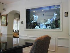 a large fish tank is mounted to the wall above a dining room table and chairs