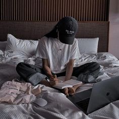 a person sitting on top of a bed with a laptop computer and papers in front of them