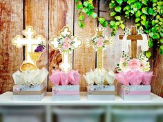 three small boxes with flowers in them on a table next to a cross and other decorations