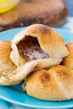 some bread rolls on a blue plate with a lemon slice in the middle and one cut open