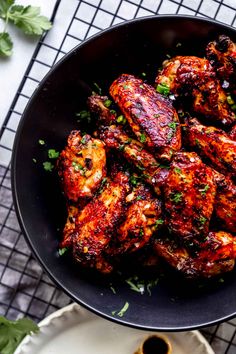 chicken wings in a skillet with parsley on the side next to some dipping sauce