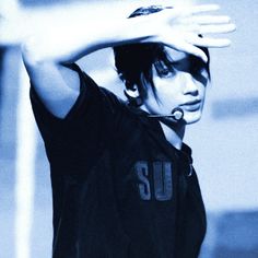 a young man wearing a black shirt holding his hand up to his head