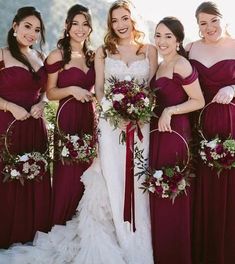 a group of women standing next to each other wearing dresses and holding bouquets in their hands